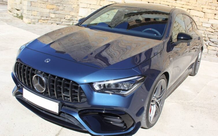 Vista frontal superior izquierda del CLA 45 S AMG 4MATIC+ con capó azul metálico, resaltando líneas de diseño y faros LED.