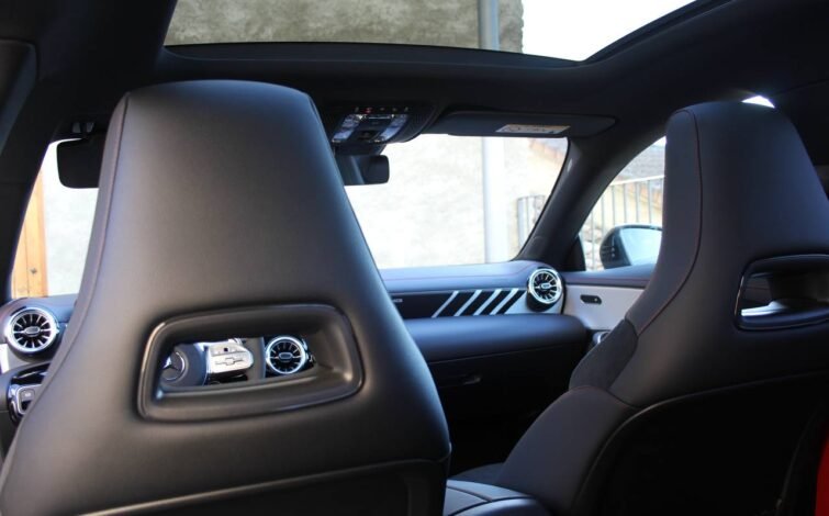Interior del Mercedes-Benz CLA 45 S AMG visto desde los asientos traseros, destacando el techo panorámico y detalles del salpicadero.