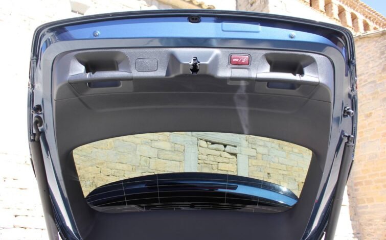 Vista desde el interior del portón trasero del CLA 45 S AMG, mostrando el botón de cierre eléctrico y manijas de sujeción.